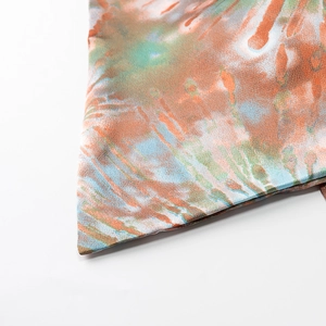 Close-up of tie-dye fabric with orange and green patterns on a strapless tube top