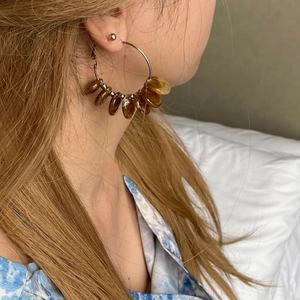 Detail of silver hoop earrings with amber resin leaf charms worn by a model