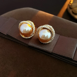 Macro shot of pearl stud earrings with double row cubic zirconia halo and gold finish