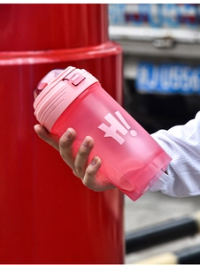 Close-up of pink plastic fitness shaker bottle with carry handle held by a hand