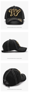 Detail of yellow towel embroidered W patch and distressed brim on black cotton baseball cap