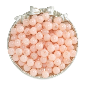 Top view of pink glass beads for jewelry making in a decorative silver bow plate