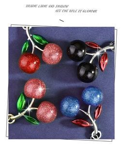 Close-up of four glitter cherry keychains in red pink blue and black metallic finishes