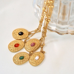 Vintage gold necklaces with oval stone pendants in five colors on white fabric