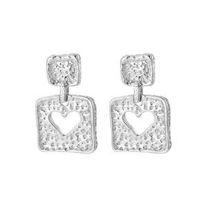 Detail of silver square earrings featuring hollow heart design and hammered metal texture