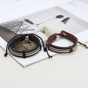 Close-up of layered black and brown leather braided bracelets on a magazine page