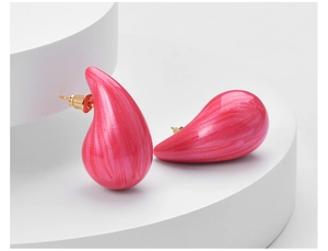Macro detail of glossy pink teardrop earrings with a golden post and marble texture