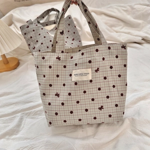 Détail d'un sac cabas en toile à carreaux vert clair avec des pois bruns et broderie