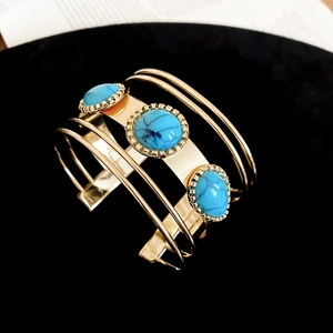 Detail of bohemian gold open cuff bracelet featuring triple blue turquoise stones