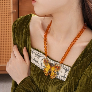 Close-up of vintage butterfly pendant with amber beads and sparkling rhinestones