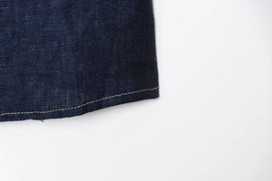 Detailansicht aus dunkelblauem Denim-Stoff mit verstärkter Doppelnaht am Saum