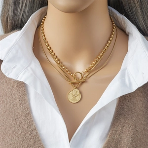 Dettaglio della collana multistrato in acciaio al titanio dorato con ciondoli a moneta