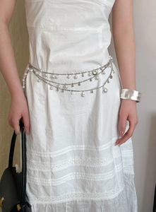 Detailed view of layered silver waist chain with elegant pearls and star charms on model