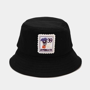 Close-up of black cotton bucket hat with vintage stamp embroidery patch and text