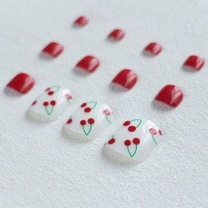 Detailed view of red cherry pattern and solid red glossy press-on toenails