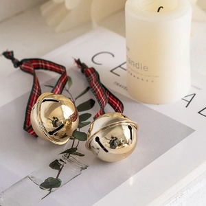 Festive gold Christmas bells with red green plaid ribbon on a warm lifestyle background