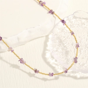 Detailed macro view of golden beads and irregular purple stones on a handmade necklace