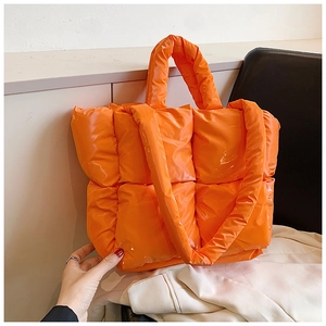 Detail of orange quilted tote bag featuring glossy waterproof fabric and padded texture