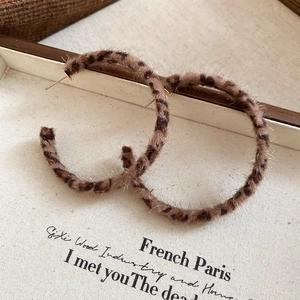 Close-up of vintage large hoop earrings featuring brown leopard print plush faux fur texture