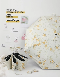 Detail of automatic folding umbrella with cream floral patterns and matching bow ornament