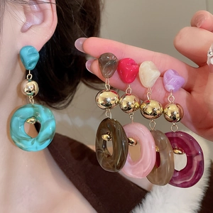 Detailed view of colorful irregular acrylic hoop earrings with gold metal accents