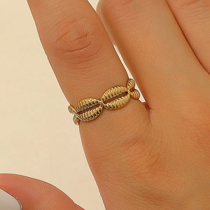 Close-up of golden seashell-shaped stainless steel ring worn on finger with refined textures