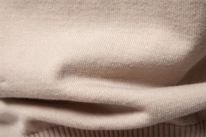 Macro view of light beige knit fabric showing fine texture and soft fiber details