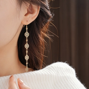 Close-up of gold vintage hollow geometric drop earring on model with white sweater
