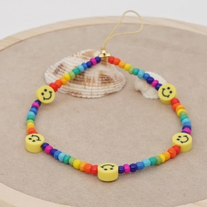 Rainbow beaded phone charm with yellow smiley faces on a natural beige background