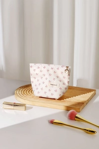 Détail de la trousse à maquillage fleurie avec fermeture éclair dorée et étiquette