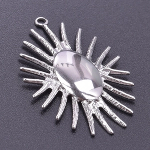 Close-up of a silver sun-shaped stainless steel pendant with radial textured sunbeams