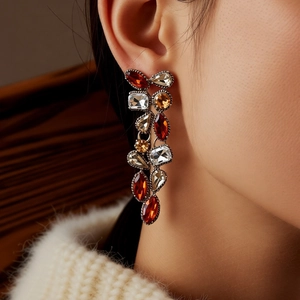 Close-up of vintage drop earrings featuring multicolor gemstones on a fashion model