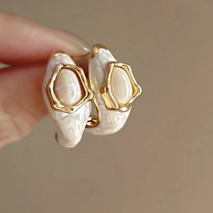 Detail of hand-held gold-edged baroque pearl earrings with vintage fringe style