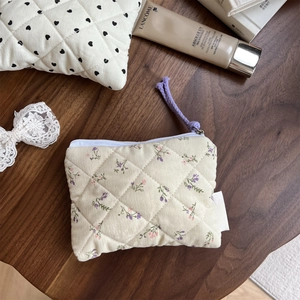 Macro view of floral quilted cotton pouch with diamond stitching and purple zipper pull