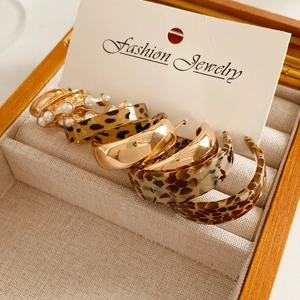Set of six pairs of gold C-shaped earrings with leopard print and faux pearls in a box