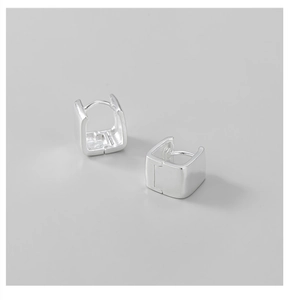 Macro detail of geometric square silver earrings with high-polish minimalist finish
