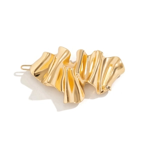 Detail of minimalist gold wavy liquid metal hair clip with a polished irregular surface