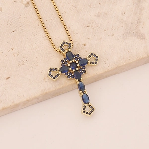 Macro shot of gold cross necklace featuring deep blue zircon stones on textured stone background