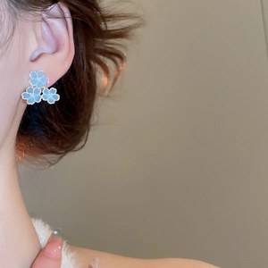 Gros plan de boucles d'oreilles fleurs en résine bleue avec bords dorés sur un mannequin