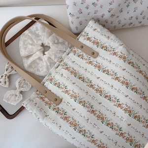 Détail du cabas en coton à motifs floraux orange et poignées en cuir élégantes