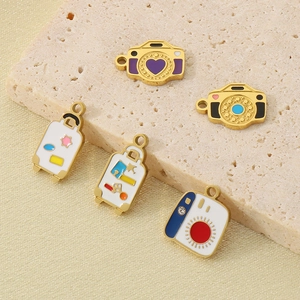 Detailed macro view of colorful camera and suitcase enamel charms with 18k gold plating