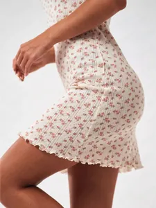 Detailed view of floral knit fabric with ruffled hem on a slim-fit mini dress