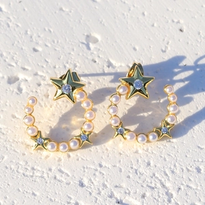 Gold-plated star and moon earrings with micro-set zircon and pearls on white surface