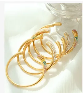 Détail de bracelets plaqués or 18k avec perles et gemmes arc-en-ciel sur de la soie blanche
