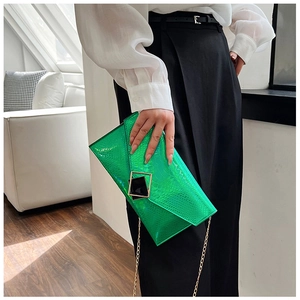 Dettaglio della pochette a busta verde brillante con trama coccodrillo e catena d'oro