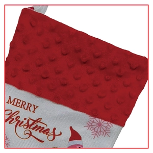 Detail of red plush cuff and golden Merry Christmas printing on white fabric stocking