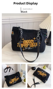 Detail view of black canvas tote bag with colorful embroidery and chain handles
