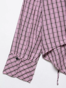 Détail de chemise à carreaux rose et marron montrant le bouton et la texture du tissu