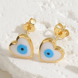 Macro view of heart-shaped evil eye stud earrings with blue enamel and gold plating
