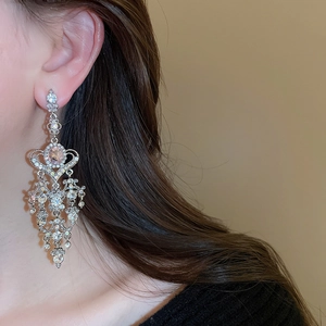 Close-up of sparkling heart tassel earrings with silver finish and crystal stones